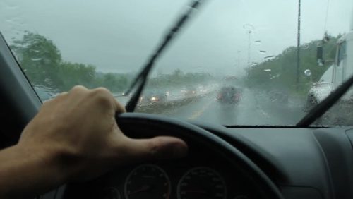 Hand gripping a steering wheel in poor weather conditions